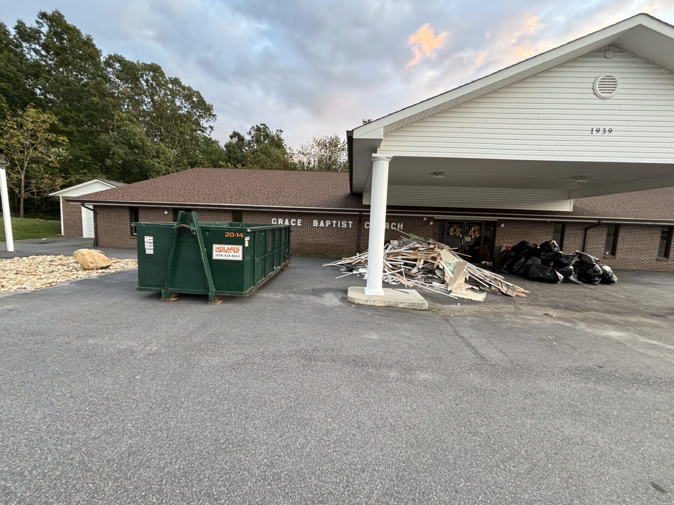 Green dumpster in Catawba, NC next to a building